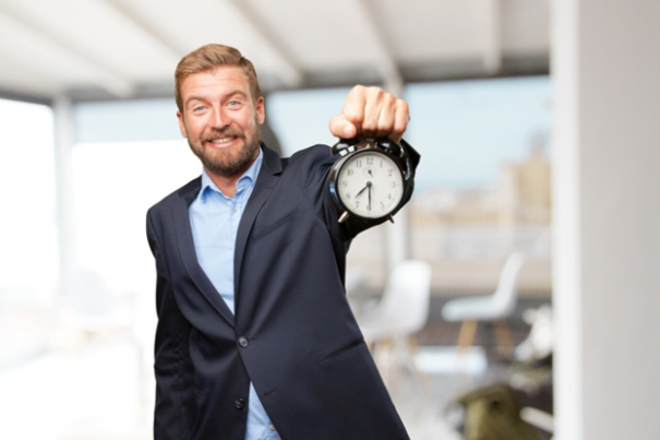 A man in a suit holding a clock, symbolizing time management and professionalism.